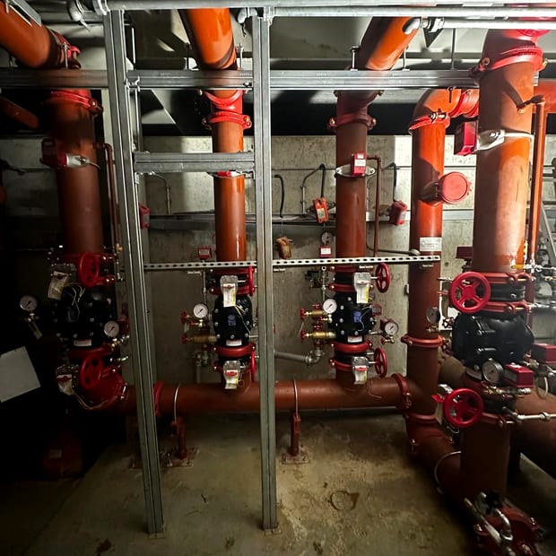 A bank of sprinkler alarm valve sets with gauges in a plant room