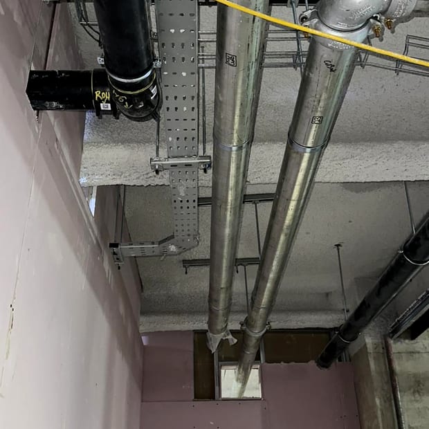 New grey dry riser pipework run through a service void, installed and awaiting completion