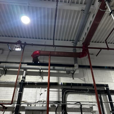 High level sprinkler main under an exposed metal deck