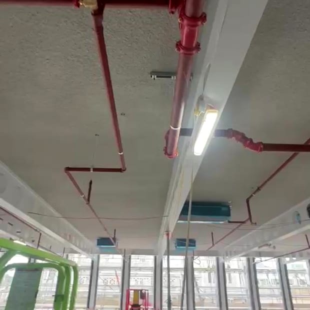 An engineer installing sprinkler pipework from a scissor lift