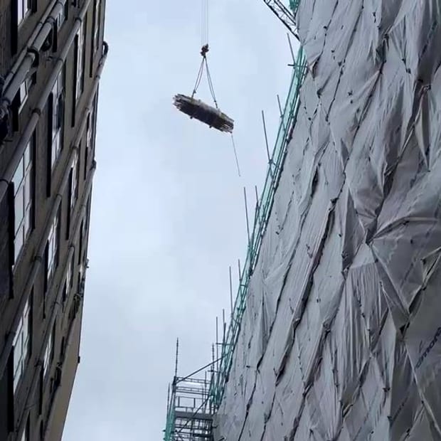 A bundle of sprinkler pipework lifted by tower crane to level 6 of a building under construction